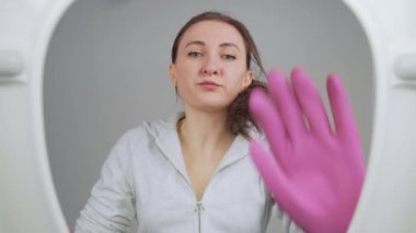 Kadın tuvaleti fırçayla temizliyor. Tuvalette temizlik ya da düzenleme için beyaz gömlek ve pembe eldiven giymiş bir kadın. Kadın temizlikçi ev hanımı. Tuvaletin dibinden bak. Temizlik