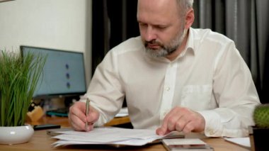 Hesap makinesi ve dizüstü bilgisayarı ofis masası, vergi, rapor, muhasebe, istatistik ve analitik araştırma için kullanan bir adam. Erkek Freelancer evden çalışıyor. İnternet taranıyor, sosyal kullanılıyor