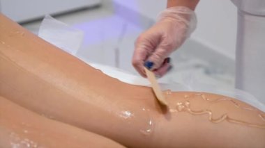 Uzman güzellik uzmanı genç bayan bacağına tüy dökücü jel sürmüş. Güzellik epilasyonu kozmetoloji ve spa konsepti