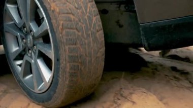 Araba ıslak, yapışkan kumda sağa dönüyor. Aracın dönen çarkı kapanıyor. Kirli yolda dönen lastik. Otomobil off-road