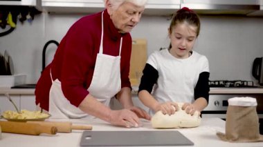 Büyükannem torununa elleri masada hamur yoğurmayı öğretiyor. Küçük kız mutfakta pizza hazırlamaya yardım ediyor. Aile tarifini genç kuşağa paylaşım bilgilerini hazırlayın