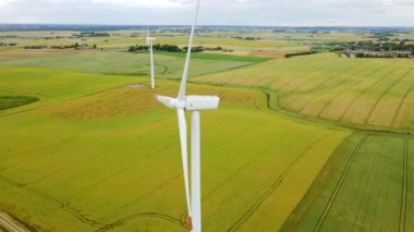 Yeşil Buğday Tarlasında Hava Görüntülü Rüzgar Türbini. Dönen bıçaklar temiz elektrik enerjisi üretir. Yenilenebilir enerji kaynaklarının popülerleştirilmesi ve sürdürülebilir kalkınma