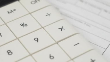 Hesap makinesi tuşları, evraklarla birlikte masada döner. Ofiste muhasebe işi kavramı. Maliyetleri hesap makinesiyle hesapla. Mali plan ve para yönetimi