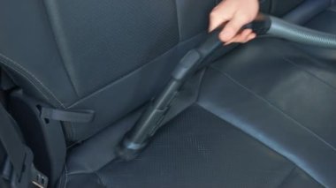 Araba yıkamada elektrikli süpürgeyle araba yıkamak. Elektrikli süpürge hortumunu tutarak ve deri koltukları süpürüp içini temizleyerek. Tamirci elektrikli süpürgeyle araba koltuğunu süpürüyor.