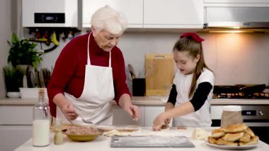 Mutfakta mutlu bir aile. Sevgili büyükannem torununa boş zamanlarında yemek yapmayı öğretiyor. Kız hamuru dikkatlice yapıştırıyor ve dolgulu turta yapıyor. Kıymalı hamur tatlısı yapmak. Konsept