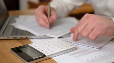 Muhasebeci, ofis masasındaki kağıt torpido gözünde iş pazarlama verilerini analiz ediyor. Şirket finans ve para muhasebesi. Ofiste dizüstü bilgisayarda çalışan profesyonel bir erkek.