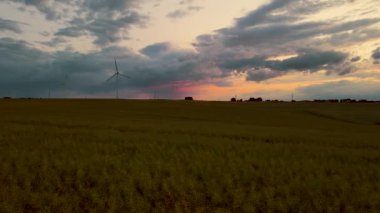 Gün batımında ve yağmurlu gökyüzünde bıçaklı Büyük Rüzgar Güç Türbinleri. Dönen bıçaklar temiz elektrik enerjisi üretir. Yenilenebilir enerji kaynaklarının popülerleştirilmesi ve sürdürülebilir kalkınma