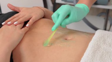 Kozmetik uzmanı ultrasonik kavitasyon için kadının karnına jöle sürüyor. Kadının midesinde obezite sorunu var. Makine kozmetolojisi. Selülit önleyici program form düzeltmesi
