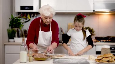 Büyükanne ve torun mutfakta hamur mayasıyla çalışıyorlar. Sevimli küçük kız kıyma ile ev yapımı hamur tatlısı yapmayı öğreniyor. Çocuk hamur yontuyor. Aile yemekleri bilgi ve deneyimi paylaşır.