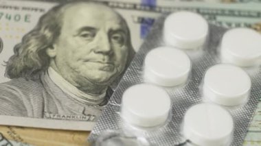Kabarcıklarda beyaz haplar, kapatın. Para, finans ve tablet. Tıbbi ilaçların maliyeti. Dolarların üzerindeki su toplayan haplar, pahalı ilaçlar, ilaç işi.