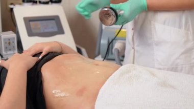 Kozmetik doktoru programı seçiyor ve güzellik salonundaki yağ ve selülitlerle savaşmak için karın bölgesinde oyuk açma işlemine başlıyor. Kadın mide için anti-yağ tedavisi görüyor, yakın çekim. Donanım