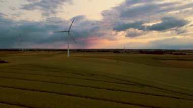 Yel değirmeni türbinleri ekolojik elektrik, modern teknoloji, tarım buğday tarlasında rüzgâr jeneratörü yağmurlu bulutlarla birlikte inanılmaz bir günbatımı altında üretir. Elektrik, ekolojik tasarruf ve alternatif