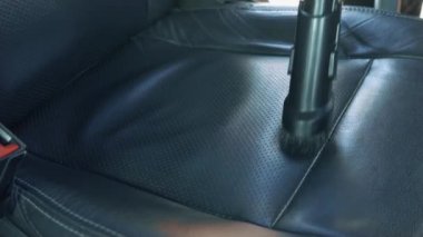 Profesyonel adam araba yıkamada araba yıkar ve içeriyi süpürürdü. Elektrikli süpürgeyle araba koltuklarını pislikten temizleyin.