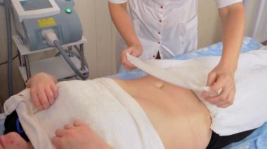 El doktorları kadın hastalarını kriyolipolisis prosedürü için hazırlıyor. Vücut bakımı. Kadının midesinde obezite sorunu var. Makine kozmetolojisi. Selülit önleyici program form düzeltmesi