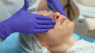 Kozmetik uzmanı, güzel beyaz bir kadının yüzü olan yıkama, nemlendirici tıp kremi için özel temizlik jeli uyguluyor. Yüz bakımı Yaşlanmaya karşı Kozmetik Masaj