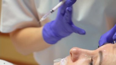 Güzellik uzmanı genç güzel bir kadının alnına botulinyum toksin enjekte ediyor. Güzellik salonundaki kozmetoloji prosedürü, deneyimli uzman kadın yüzüne botulinyum enjekte ediyor.