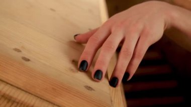 Güzel siyah manikürlü genç bir kızın eli kaplıcadaki ahşap dokunun üzerinde nazikçe koşuyor, rahatlığın tadını çıkarıyor. Sauna, spa salonu, sağlık için sağlıklı bir fıçı.