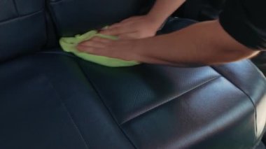 Oto sürtünerek parla. Garajda arabanın iç tarafıyla ilgilenen adamın yan görüntüsü. Arabanın içini temizlemek ve deri koltuğa dezenfekte sıvısı sıkmak.