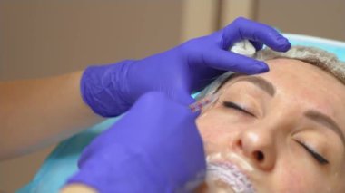 Güzellik doktoru, genç ve güzel bir kadının iğnesini yapar. Yüzü mükemmeldir. Kozmetik uzmanı ilaç iğnesi ve şırınga kullanıyor. Kozmetik enjeksiyonlar, gençleştirme yüzü