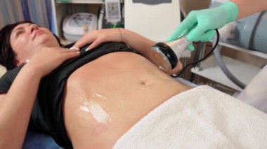 Kadın, vücut hatları ve anti-selülit terapisi için ultrason havza tedavisi görüyor. Donanım bazlı. Cavitasyon tedavisi. Kadının midesinde obezite sorunu var.