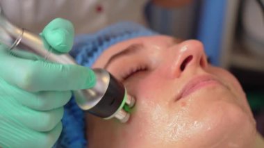 Ultrason boşluğu yüz gerdirme prosedürünü kapatın. Kadın hasta kozmetoloji kliniğinde, doktor güzellik prosedürü uyguluyor. Yaşlanma karşıtı yüz gençleştirme. Kozmetolojide ultrason yüz kaldırma