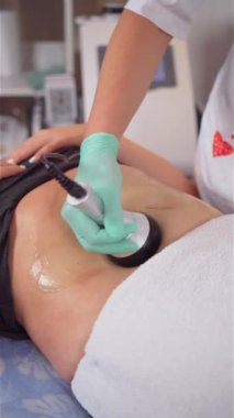 Kadın mide için anti-yağ tedavisi görüyor, yakın çekim. Dikey ultrason boşluğu ve vücut bakımı. Donanım kozmetolojisi. Selülit karşıtı terapi