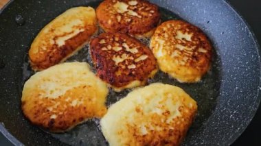 Süzme peynirli krep pişiriyorum, yakın çekim. Syrniki kızartma tavasında yağda kızartılır. Yemek pişirme süreci. Lezzetli bir kahvaltı. Çocuklar için yiyecek. Kaymak tabağı.