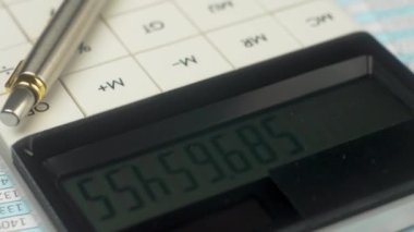 Para saymak için düğmeleri kapatan beyaz modern hesap makinesi. Belge ve kalem masanın üzerinde. Piyasa büyümesi durumunun analizini ve şirket satışlarını tartışın. Vergi indirimi formu veya belge ve