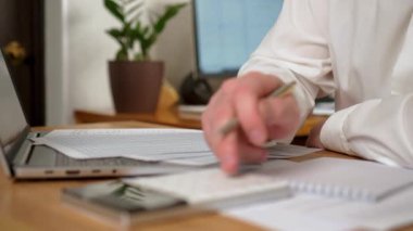 Ofiste Masada Oturan Adam özenle kağıt parçasına, Maliyetleri ve Maliyetleri Hesaplayan Adam, kapat. Erkek Freelancer evden çalışıyor. İnternet taranıyor, sosyal ağlar kullanılıyor