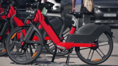 Kiralık kırmızı bisikletler. Elektrikli bisiklet şarj istasyonu. Şehrin arka planına park edilmiş elektrikli bisikletleri paylaşıyoruz. Çevre dostu kentsel sağlıklı ulaşım
