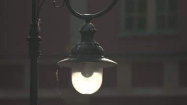 Bulanık Arkaplan Karşısında Yumuşak Güneş Işığıyla aydınlatılan Klasik Sokak Lambası. Vintage sokak lambası tek başına, güneş ışığı filtrelerken sıcak bir parıltı saçıyor, klasik dizaynını ortaya çıkarıyor.