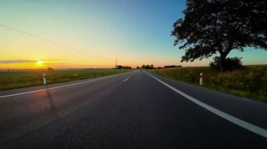 Polonya 'da gün batımında araba sürmek. Yol boyunca çarpıcı POV görüntüleriyle otoyolda, keşif gezileri, aktif dinlenme, seyahat, neşe