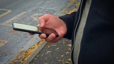 Erkek el kameraları akıllı telefonları ve mobil uygulamalardaki kaydırmalı sayfaları yolda bekleyen cep telefonu aygıtlarına kaydeder. Akıllı telefonu olan ve haber sosyal medyasında gezinen adamı kapat