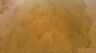 Kumsaldaki hava manzaralı kum desenleri. Sığ su, kumun dokusunu ortaya çıkarır. Eşsiz ve büyüleyici bir görsel görüntü yaratır. Doğa arkaplan, duvar kağıdı, metin yerleştirmesi için doku oluşturdu