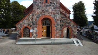 Polonya Köy Mezarlığının Kalbindeki Katolik Kilisesi Taş Mimarisini ve Huzurlu Çevresini Günışığında Gösteriyor. Katolik katedrali, din, Katoliklik, Tanrı ile komünyon.