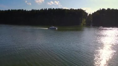 Serene Nehri boyunca süzülen motorlu tekne Ilık Öğleden Sonra Günışığında Lush Ormanı ile çevrilidir. Sürat teknesi huzurlu nehir boyunca sürükleniyor, sık ormanlarla çevrili, öğleden sonra güneşinin yumuşak sıcaklığı altında.