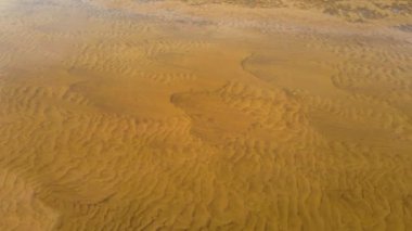 Göl tabanındaki hava manzaralı kum desenleri. Sığ su, kumun dokusunu ortaya çıkarır. Eşsiz ve büyüleyici bir görsel görüntü yaratır. Doğa arkaplan, duvar kağıdı, metin yerleştirmesi için doku oluşturdu