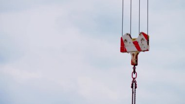 Kilitlenmiş vinç kanca bloğu açık gökyüzüne karşı tel askılarda asılı. Yükseklerde çalış. İnşaat alanındaki vinç kulesini kapatın.