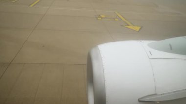 Pist boyunca taksicilik yapan uçak, Hava Limanı 'nda Bulutlu Gün' de türbin görüntüsünü gözler önüne seriyor. Uçak pistte taksicilik yapıyor, bulutlu gökyüzünün ortasındaki kalkış pozisyonuna doğru hareket ederken türbinin yakın görüntüsünü gösteriyor.