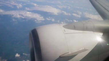 Uçak Kanadı ve Motor Manzarası Gündüz Uçuşu sırasında Pofuduk Bulutların Üzerinde Görünüyor. Jet motoru güneş ışığını yansıtan kanatların yanında