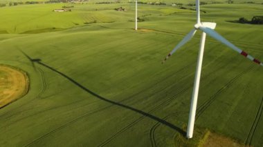 Rüzgardan gelen elektrik enerjisi jeneratörden geçiyor. Kırsal alanda dönen bıçakları olan bir yel değirmeni. Zararlı emisyonların en aza indirgenmesi yoluyla çevresel sürdürülebilirlik