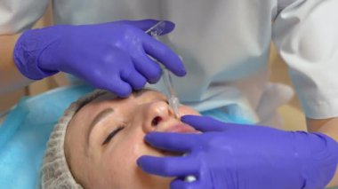 Dudak büyütme için enjeksiyon prosedürü, kapat. Yüz bakımı, gençlik ve güzellik reklamları. Kozmetik uzmanı yavaşça ve dikkatlice müşteri dudaklarına dolgu yapar.