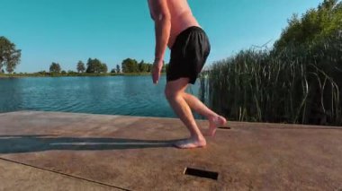 Sakar, kilolu bir adam soğuk, ferahlatıcı suya balıklama atlıyor. Kel tombul adam mavi göle daldı. Eğlence, aktif yaşam, hayatı kucaklama, maceralar