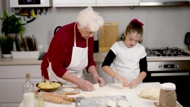 Güzel küçük kız, sıcak beyaz mutfağı doldurarak mantar hamuruyla iyi iş çıkarıyor. Granny 'nin aşçılık dersleri olumlu gidiyor. Büyükanne ve torun evde turta hazırlıyorlar.