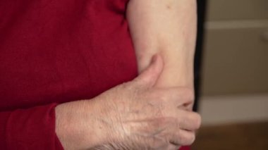 Yaşlı kadın dirseğine masaj yapıyor. Yaşlı yaşlı kadın eklem ağrısı var, yaralanmış, elini çekiyor ve ağrılı kasları ovuyor. Artrit, artrosis ve yaşla ilgili diğer kemik hastalıkları. Dikkat