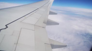 Açık Gün 'de Uçak Zarifçe Bulutların Üzerinde Uçuyor, Kanat Gösterme ve Genişletici Mavi Gökyüzü. Uçağın kanatları bulutların üzerinde yükseliyor.