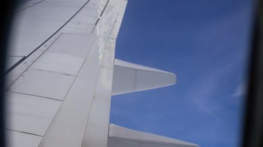 Pofuduk Beyaz Bulutlar Gün ortası uçuşu sırasında Parlak Mavi Gökyüzünde süzülüyor. Uçak kanadı, kabarık beyaz bulutlarla dolu parlak mavi gökyüzüne kadar uzanıyor.