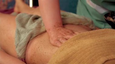 Kızlar lüks kaplıca salonlarında vücuda masaj yapmaktan hoşlanırlar. Pratisyen masör, kadın müşterinin karnına kremalı ovalayarak masaj yapıyor.