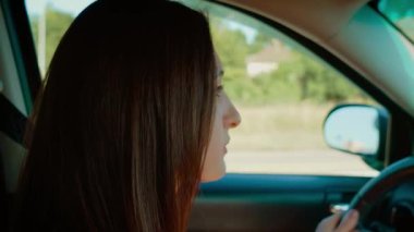 Odaklanmış araba kullanan kadın, yolda giderken konsantrasyon ve sakinlik gösteren ifade. Kadın sürücü sakin ve dikkatli bir görünüm sergiliyor, sürüş deneyimine dalmış. Bayan fışkırıyor.