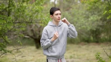 Orada koşan genç bir çocuk portresi, nefes alma eğitimi ve dayanıklılık. Genç adam yerinde koşuyor, dayanıklılığını ve nefesini geliştirmeye odaklanıyor. Ergen çocuk dayanıklılığını arttırmak için koşuyor.